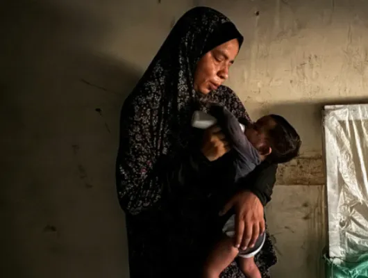 A woman feeding a child with a bottle. 