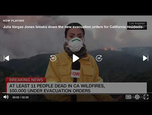 screenshot of tv reporter with fires burning on hillside behind her