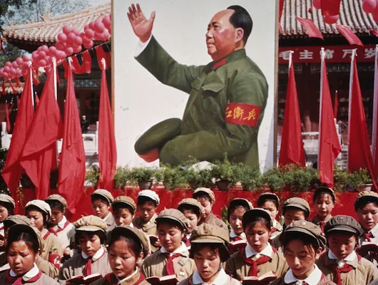 Photo of people in front of large poster of Mao Tse-tung