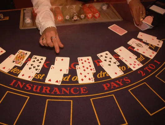 Photo of hands of a black jack dealer and cards on a gaming table 