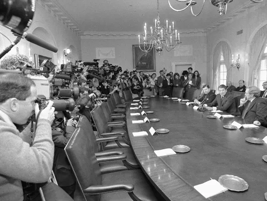 Media surround a table occupied by former President Ronald Reagan