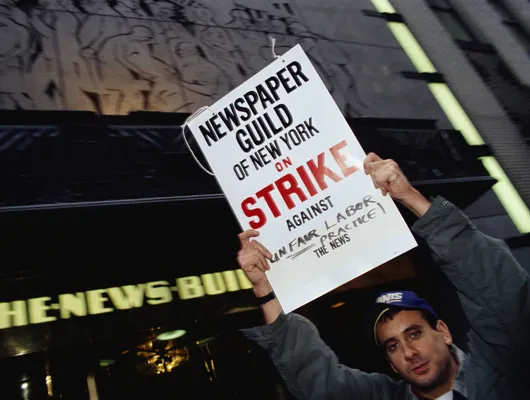 Man holding sign reading "Newspaper Guild on Strike"
