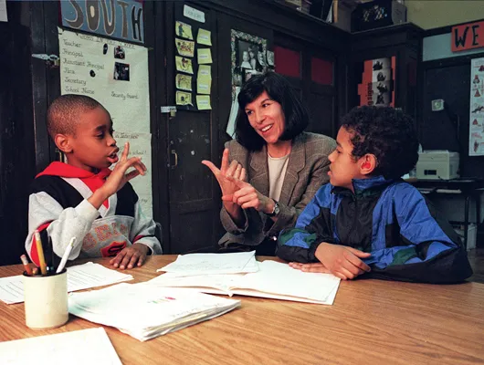 Female teacher and two students using sign language in a classroom