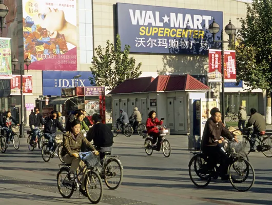People riding bikes on streets in China in front of a Wal-Mart