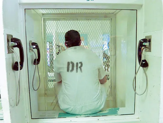 Inmate in phone cubicle behind bars