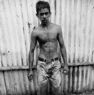Available Work Mumbai, India. For a few rupees this man climbs down head first under one of two giant pipes crossing the slum at Dharavi in filth and muck and stink to clear a sewer opening from debris.
