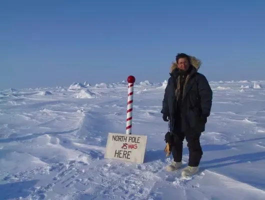 Man standing next to a sign that reads "North Pole Was Here."